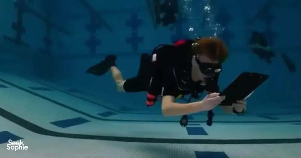 Underwater training pool scene with a diver reading a slate while practising open-water skills for Sanctum Dive Indonesia in Bali