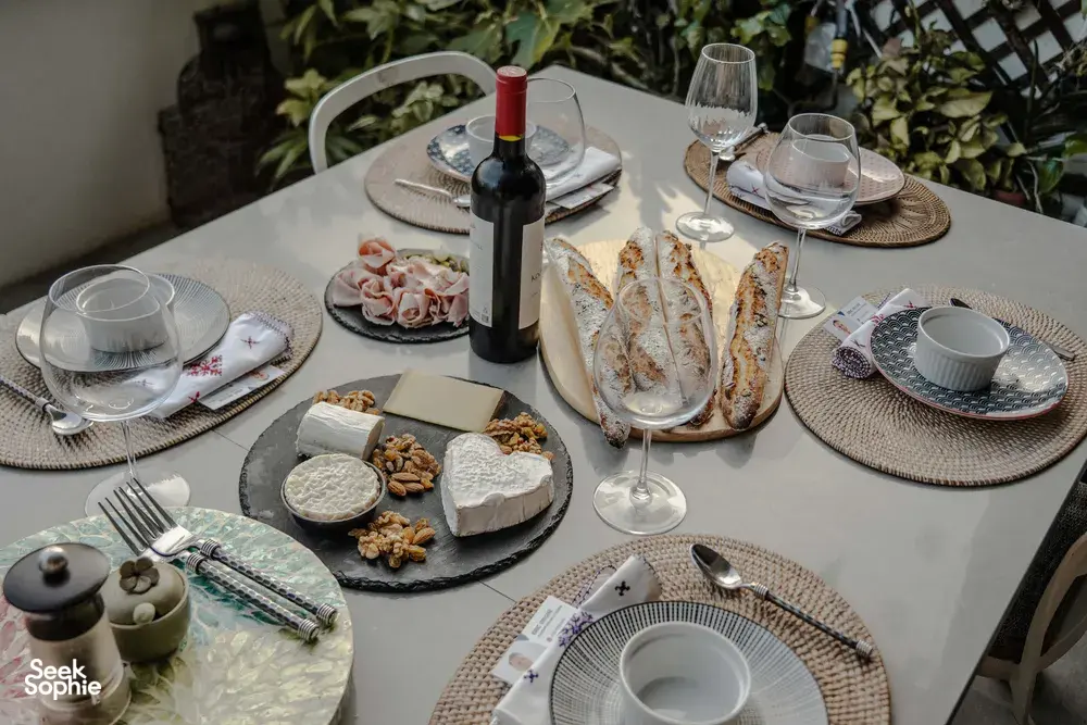 French baguette meal spread on a dining table in a cosy Singapore loft, with wine bottle and plates for sunset drinks
