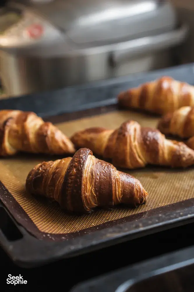 Golden croissants on a mesh baking tray cooling in the home kitchen during a French Cooking Lab class in Singapore