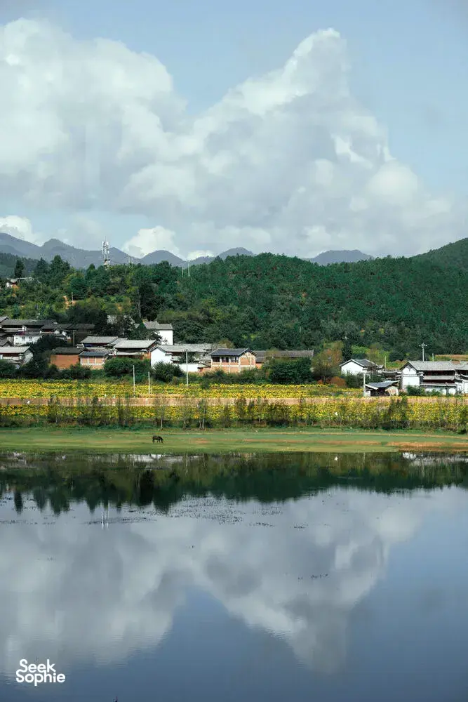Desa tepi sungai Shaxi di Dali, Yunnan, dengan danau tenang yang memantulkan atap-atap rumah dan pegunungan berhutan selama retret eco ini