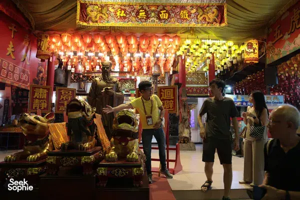 Lantern-lit Chinese temple walkway with Hey Lad Tour guide leading visitors past illuminated shrines during Hidden Chinese Rituals in Singapore, Singapore hidden gems