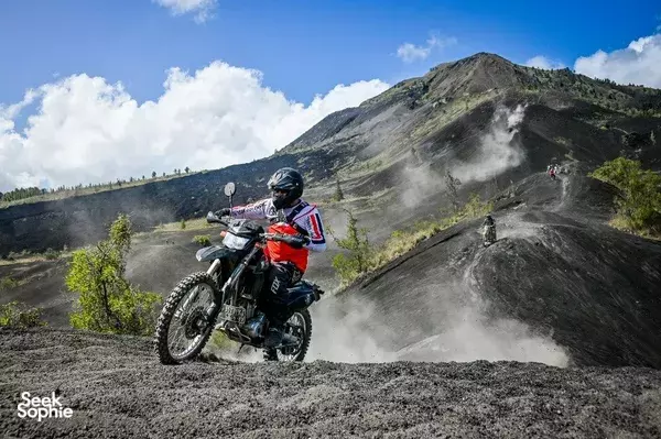 Enduro rider leaning into a dusty downhill turn on rugged volcanic trails through Bali towards Mt Batur