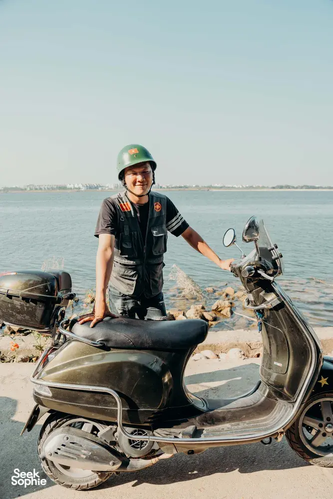 Tuyen Vu mengendarai skuter vintage di tepi pantai luar Hoi An, menangkap pemandangan sungai dan pesisir yang tenang