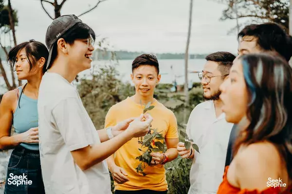 People chatting and tasting skewers outdoors at a seaside farm in Singapore during a hands-on meal experience