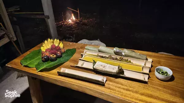 Jungle cooking ingredient prep on banana leaves beside a night campfire on a wooden table in Khao Sok National Park