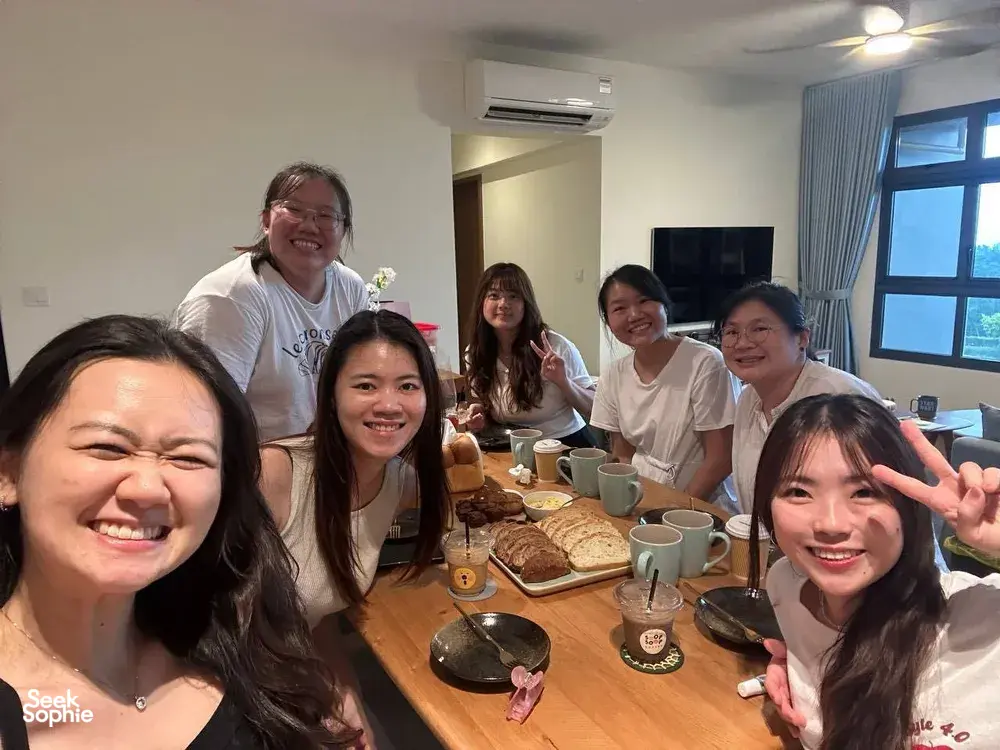Group of smiling guests at a Singapore baking class table with cups and sliced breads, posing for a photo — workshops in Singapore