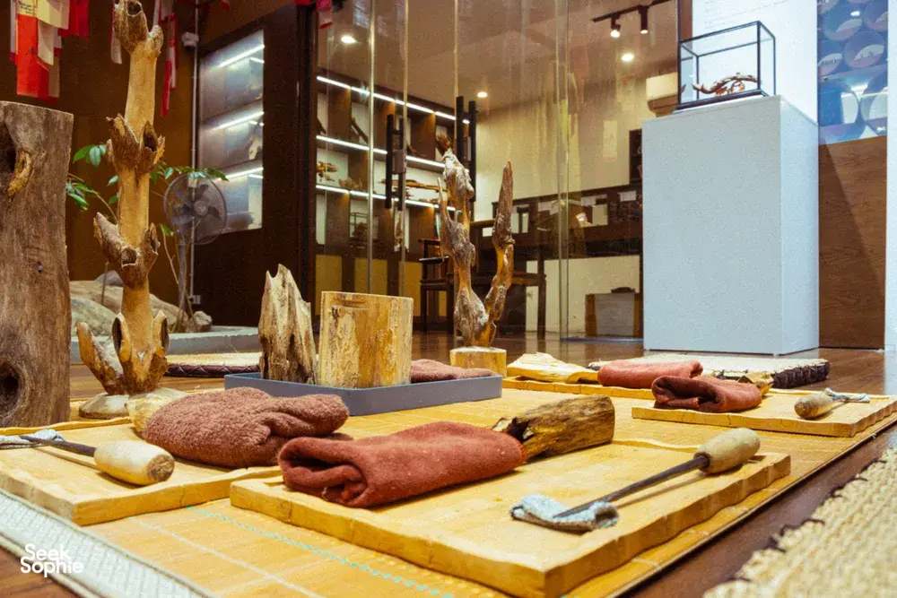 Agarwood workshop table in Hanoi with cut wood pieces and wrapped samples laid out inside an exhibition room
