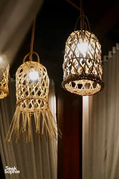 Woven pendant lanterns glowing in a rustic courtyard where a Traditional Manggarai vegan cooking class is hosted, Labuan Bajo