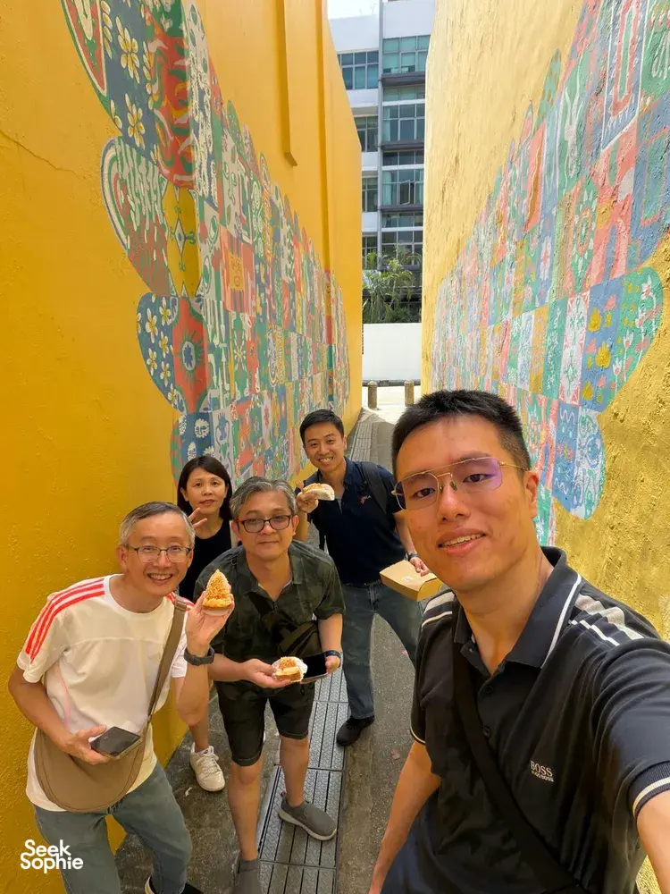 Team members holding ice creams and smiling in a colourful lane during a real-life Monopoly challenge in Katong-Joo Chiat, Singapore hidden gems