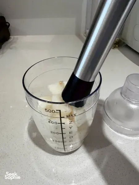 Metal blending tube over a litre-measuring beaker of pale mixture, suggesting TCM mocktail base preparation—workshops in Singapore