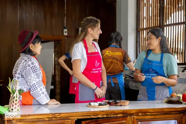 Small-group cookery class in a Chiang Mai kitchen with Eco Tours Chiang Mai, participants in red aprons preparing ingredients