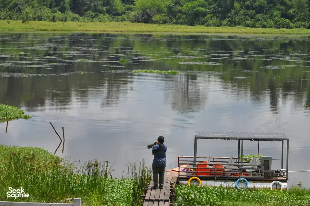 Traveller on a wooden dock by a calm river in Cat Tien with wildlife-viewing equipment, during a private 3D2N ethical tour