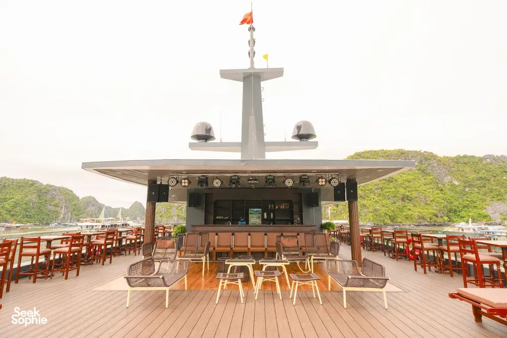 Sunshine Golden Cruises open-air dining deck with rows of tables and red chairs on a luxury Cat Ba cruise, facing the bay