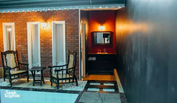 Terrace seating by a pool edge at Old Frankland Tea Estate lodge in Kandy, with brick walls and lantern-lit interior