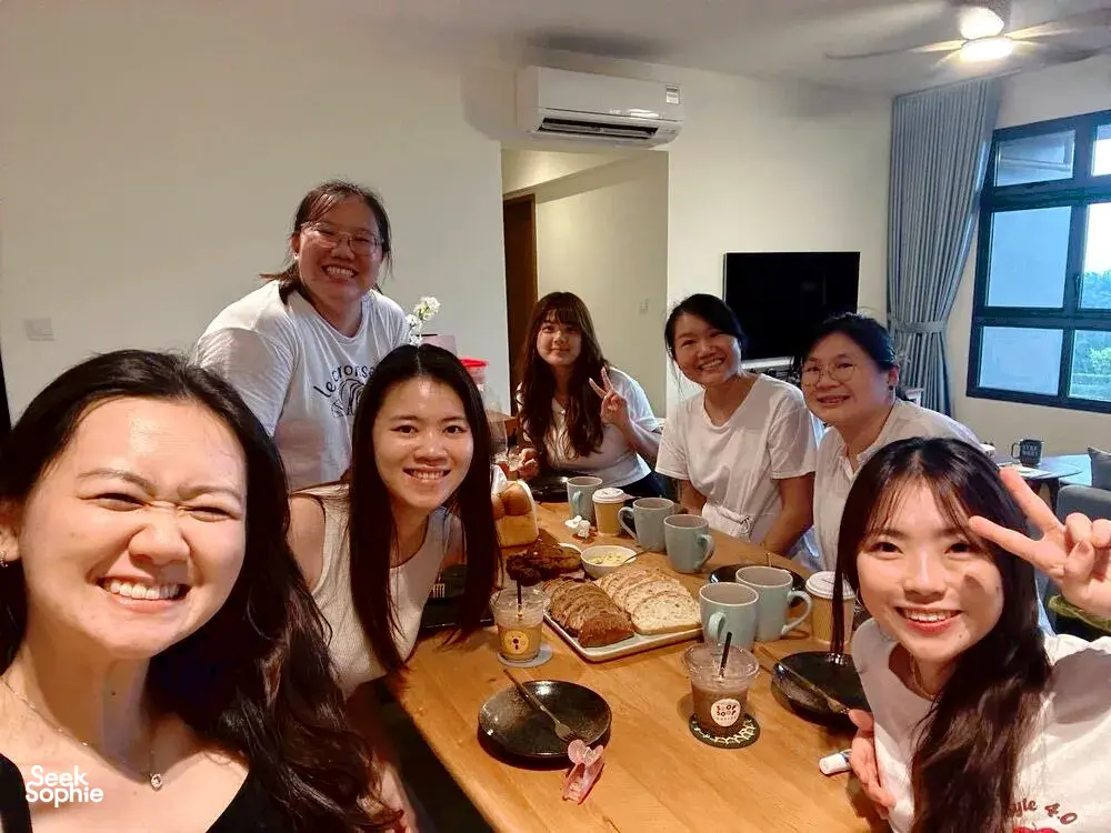 在新加坡的佛卡夏课程工作坊中,面带笑容的参与者围坐在木桌旁,桌上摆着杯子和面包