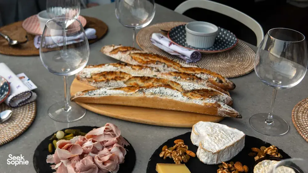 Sunset charcuterie spread with flour-dusted baguettes, sliced ham, cheese and wine glasses on a table for workshops in Singapore