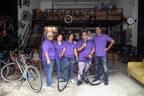 Unspokin team poses in Singapore’s bike workshop with a custom-built bicycle and spare frames behind them, workshops in Singapore