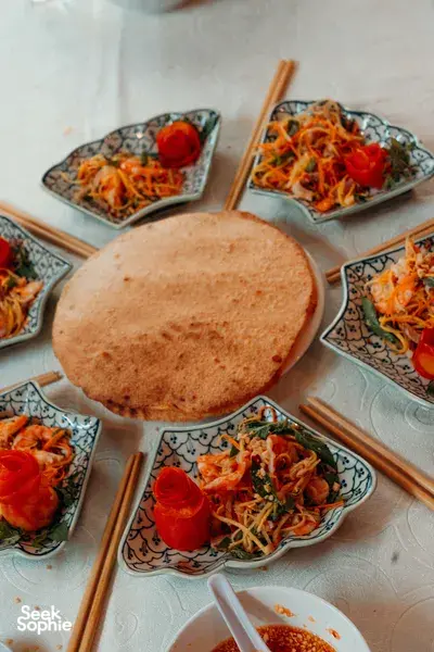 Vietnamese home-cooked spread in Hoi An: savoury pancake resting on a plate alongside bowls of shredded herbs and vegetables