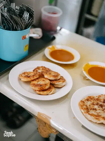 Assorted street-food snacks and dipping sauces on plates during the Joo Chiat food tour, Singapore hidden gems