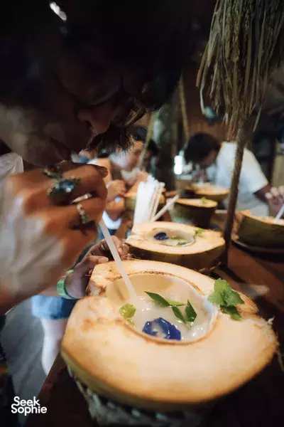 A guest spooning appetiser from a carved bread bowl at a rustic tribal farm-to-table meal in Labuan Bajo