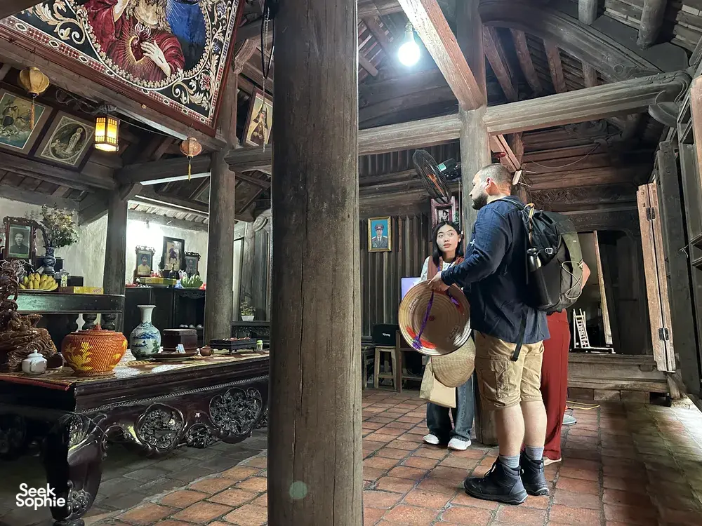 Backpackers standing in a traditional wooden home at Duong Lam ancient village near Hanoi during hands-on rice farming day