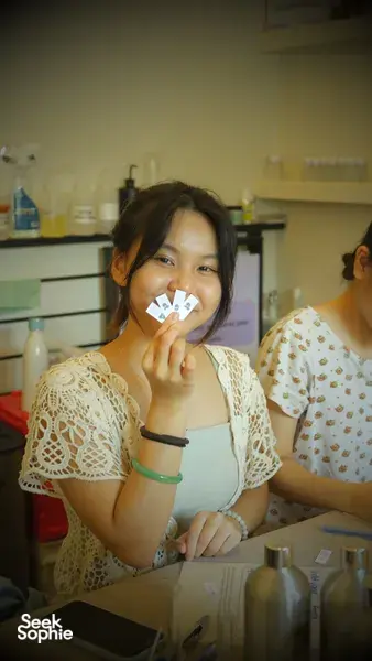 Participant holding scent sample cards while preparing personalised coco-soy candle blends at Perfume Play in Singapore candle workshop