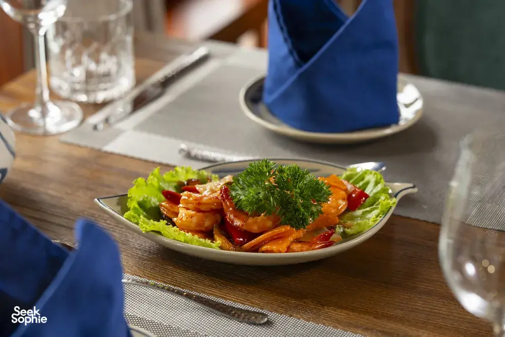Four-course-style seafood lunch on a Cat Ba boutique cruise, with shrimp and herbs served at a wooden table