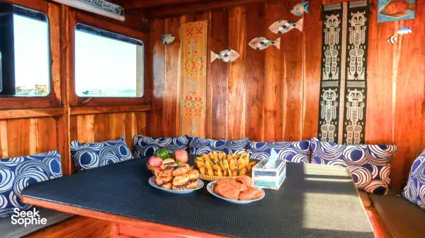 Wooden boat dining area on the 3D2N Komodo dive liveaboard, with a table set for meals served during Labuan Bajo