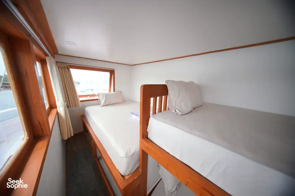 Travass Life 3D2N join-in Komodo trip twin beds in a boat cabin with window light and folded towels, Labuan Bajo