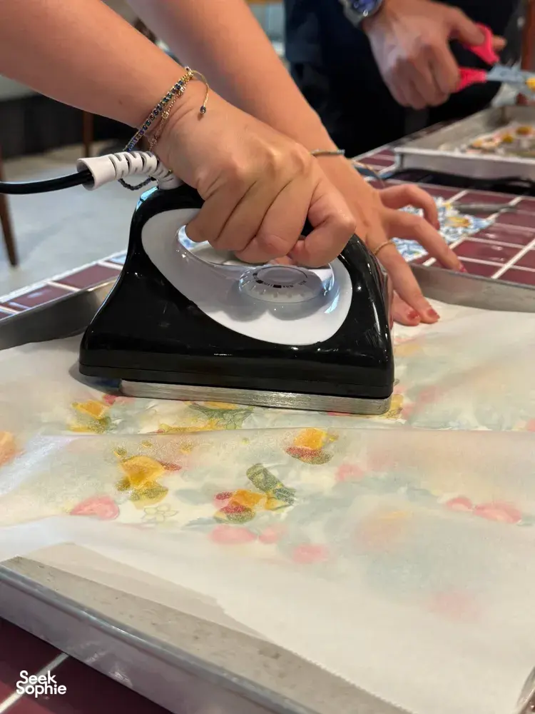 Hands heat-sealing reusable food wrap material with an iron during Agrihome sustainability workshops in Singapore