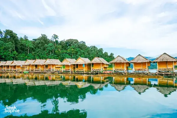 Rows of riverside thatched cottages reflected on Cheow Lan Lake at Khao Sok Riverside Cottages, a family-run stay