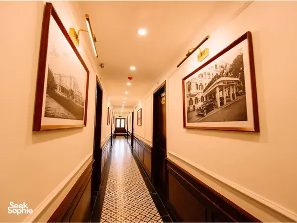 Wood-panelled corridor on a Cat Ba cruise by Sunshine Golden Cruises, lined with framed photos and patterned carpet lighting