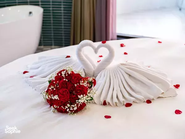 Luxury suite bed on board Doria Cruise in Lan Ha Bay, dressed with rose petals and a towel heart swan ornament