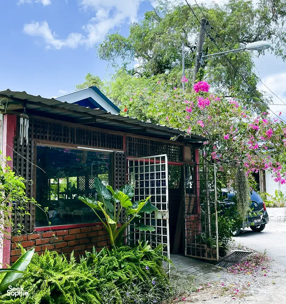Entrance to Ilham Ceramic Studio in Langkawi with garden greenery, flowering vines and a brick-lined courtyard