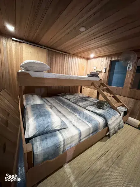 Air-conditioned houseboat cabin with wooden walls and neatly made beds on a 4D3N orangutan safari in Tanjung Puting