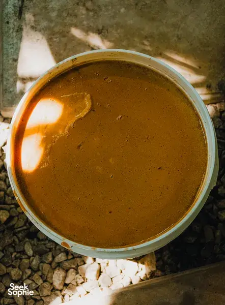 Brown palm-sugar syrup in a metal pot, warmed over stones in a Sarawak craft setting from Tanoti Crafts in Kuching