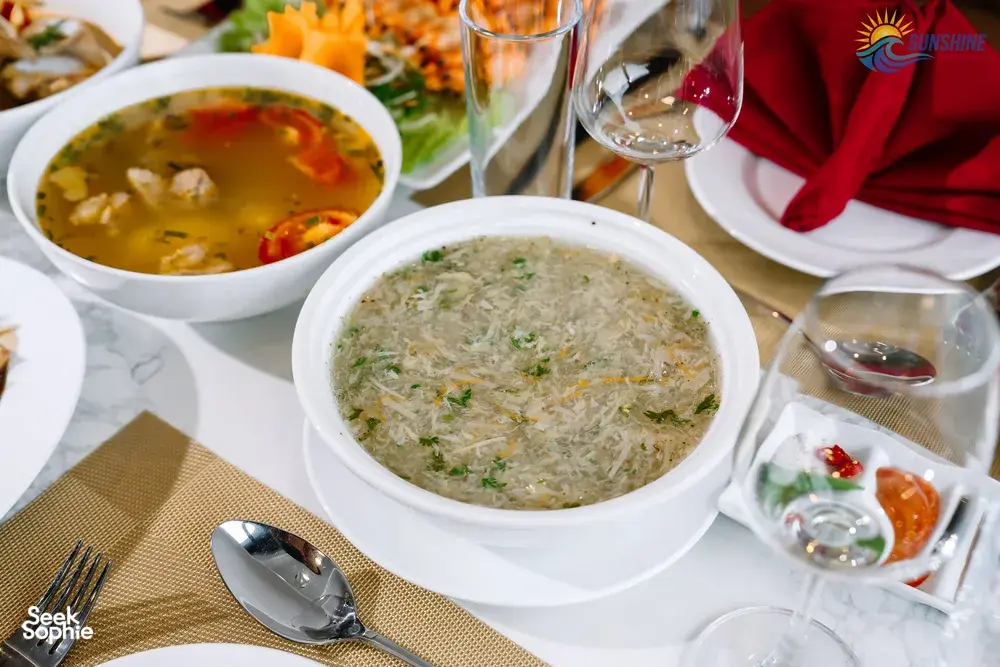 Bowls of soup and sides arranged on a table during dinner on a Sunshine Golden Cruises luxe 2D1N Cat Ba cruise