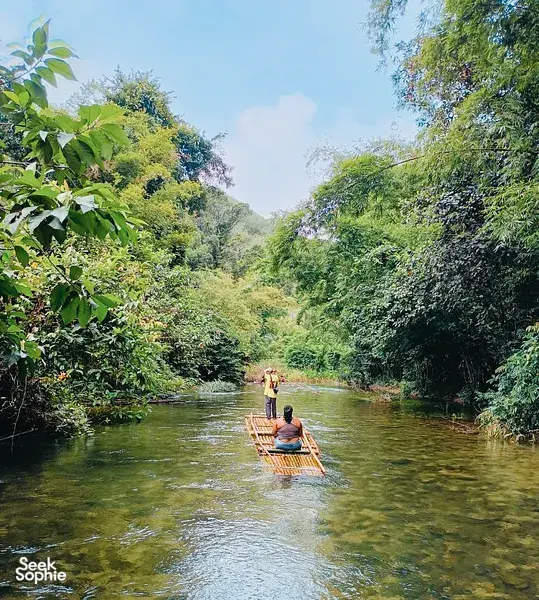 Raft on a calm river with passengers paddling through lush forest in Khao Lak, an adventure rafting moment