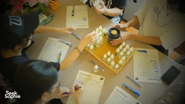 Measuring fragrance drops into small coco-soy candle jars on a table at Perfume Play in Singapore during a candle workshop