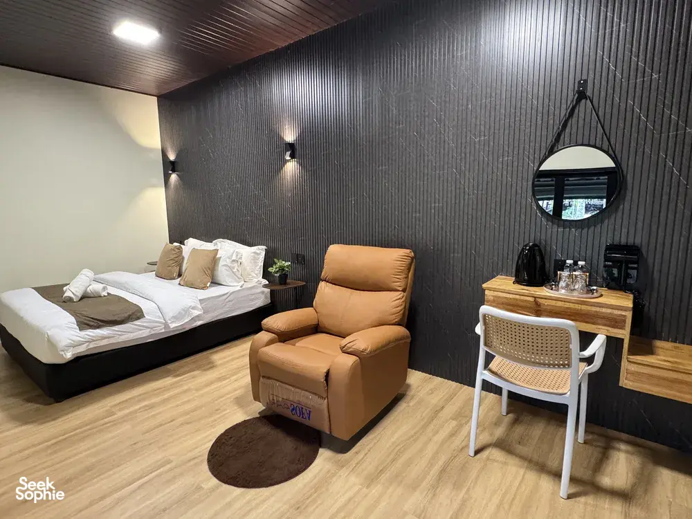 Sukau Greenview Lodge bedroom with sofa chair, coffee table and circular mirror, simple 2D1N B&B stay near the Kinabatangan River