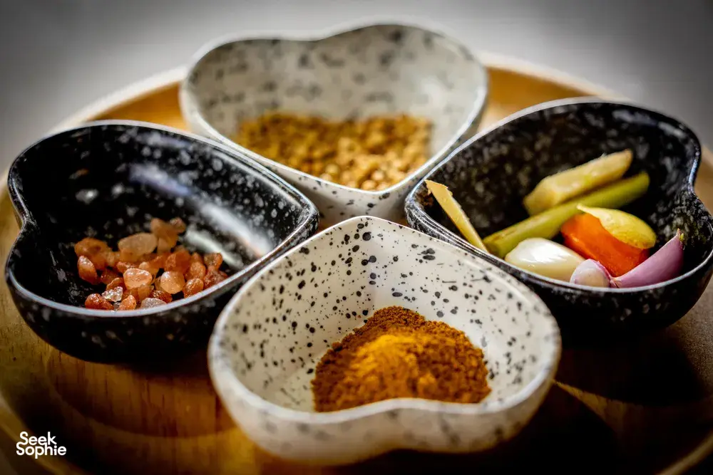 Forage-to-table cooking class ingredient bowls with spices, herbs and vegetables on a wooden table in Mae Kampong, Chiang Mai