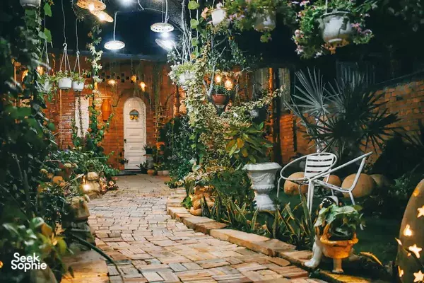 Lantern-lit garden walkway with seating at Mekong Pottery Homestay in the Mekong Delta, surrounded by plants and greenery