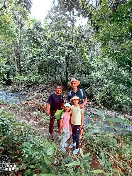 Former logger-led Lombok forest walk with a small group posing on a muddy trail through dense rainforest greenery