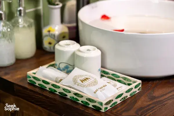 Toiletries and a tissue box on a wooden bath counter with a freestanding tub in the ensuite cabin on Cat Ba Ocean Cruises
