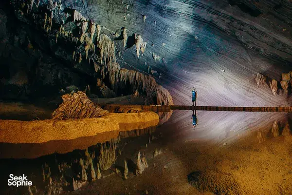 Greenland Tours cave trek in Phong Nha, with a traveller walking along a lit passage inside the limestone cavern