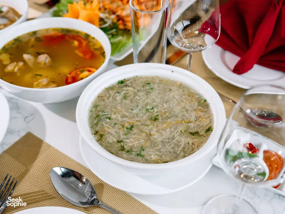 Cat Ba cruise dinner table with individual soup bowls and fresh herbs, set for a luxe 2D1N dining service