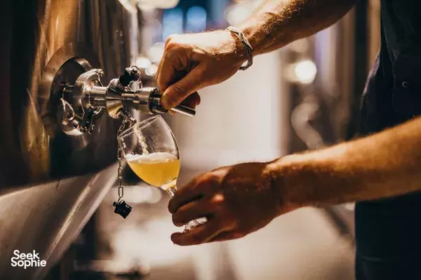Foamy beer stream fills a glass at the spout during a Lion Brewery Co brewpub tour in Singapore taproom
