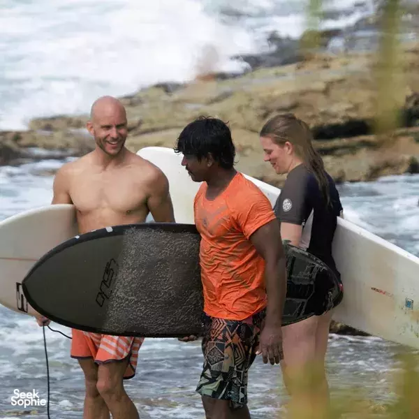 Surfboards by the boat on a choppy Weligama coastline as surfers chat before heading out for their lesson