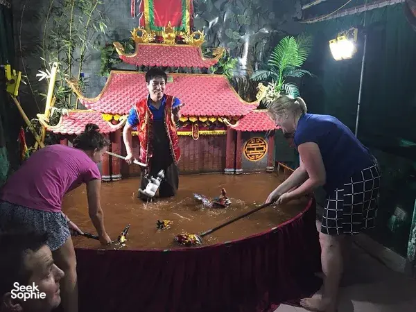 Dalang Bamboo Life di panggung wayang air Hanoi saat para tamu mendekat untuk menyaksikan pertunjukan pribadi
