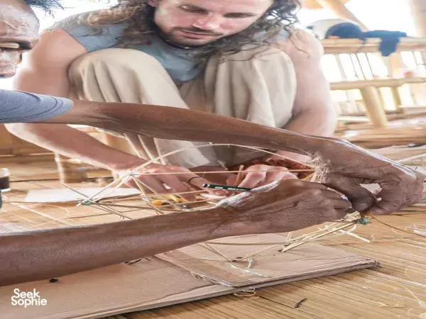 Bamboo building workshop in Bali: craftspeople lash bamboo framework together with woven ties across a worktable